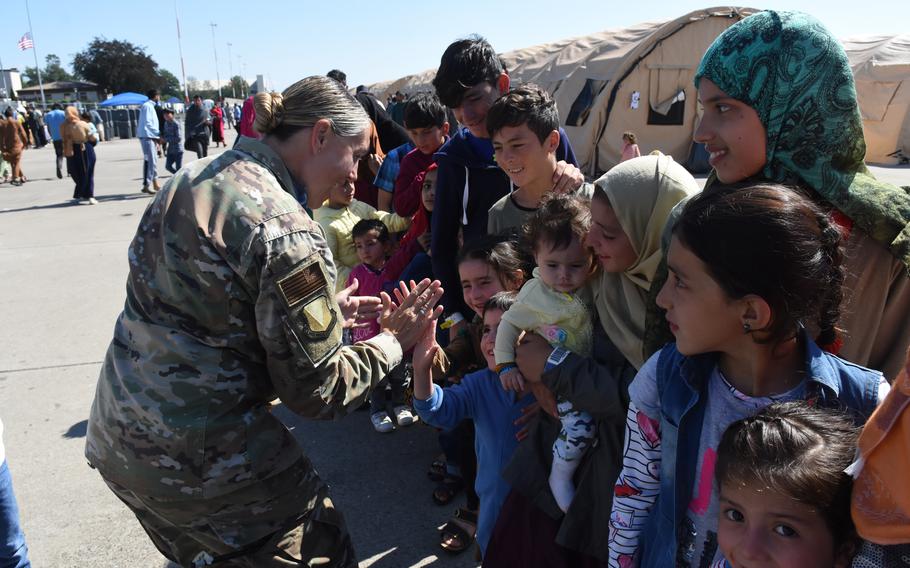 Air Force Col. Amy Glisson exchanges high-fives with Afghan children Sept. 2, 2021, at temporary living facilities at Ramstein Air Base. Glisson, the 86th Mission Support Group commander at Ramstein, is the camp commander for the day-to-day operations involving thousands of evacuees from Afghanistan.