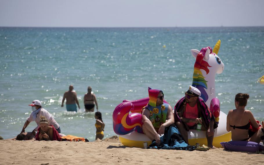 Tourists sunbathe on the beach at the Spanish Balearic Island of Mallorca, Spain, Monday, June 7, 2021. 