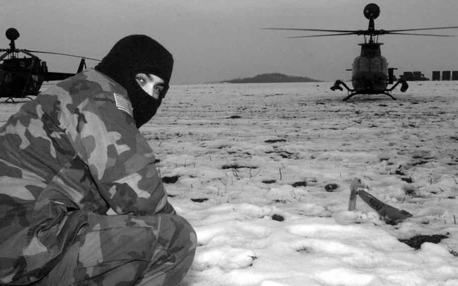 Taszar AB, Hungary, January, 1996: An American IFOR member crouches low just before an attack helicopter takes off from its snowy landing strip.