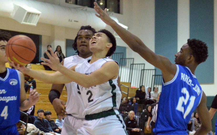 Daegu's Adrian Tagalog drives to the basket past Osan's Justiss Parker-Jones during Friday's Korea boys basketball game. The Cougars edged the Warrriors 73-70.