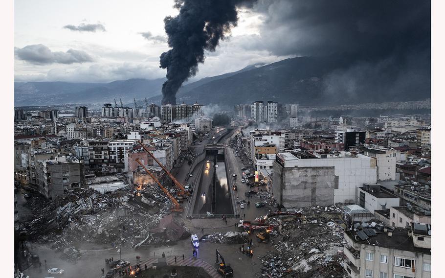 Smoke billows from the Iskenderun Port as rescue workers work at the scene of a collapsed building on Feb. 7, 2023, in Iskenderun, Turkey. An earthquake hit near Gaziantep, Turkey, in the early hours of Monday, and was followed by another 7.5-magnitude tremor. The quakes caused widespread destruction in southern Turkey and northern Syria and were felt in nearby countries.