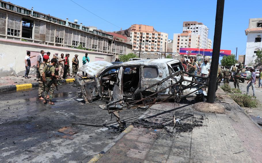 Security personnel stand amid the wreckage of a damaged vehicle at the site of a deadly car bomb attack that targeted two senior government officials, who survived, security officials said, in the port city of Aden, Yemen, Sunday, Oct. 10, 2021. Aden has been the seat of the internationally recognized government of President Abed Rabbo Mansour Hadi since the Iranian-backed Houthi rebels took over the capital, Sanaa, triggering Yemen’s civil war.