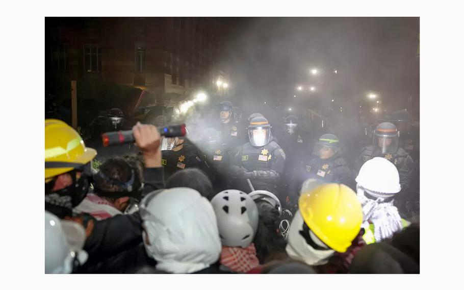 A protestor uses his flashlight on the police at the UCLA campus. 