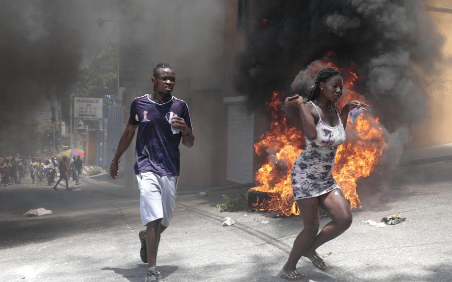 Demonstrators run past tires set on fire during a protest against insecurity in Port-au-Prince, Haiti, Monday, Aug. 7, 2023. 