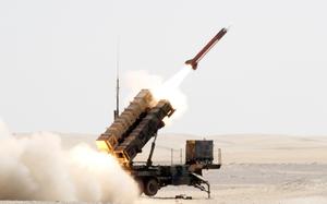 Flames shoot out the back of a missile as it is launched from a vehicle-mounted launcher with a desert horizon in the background.