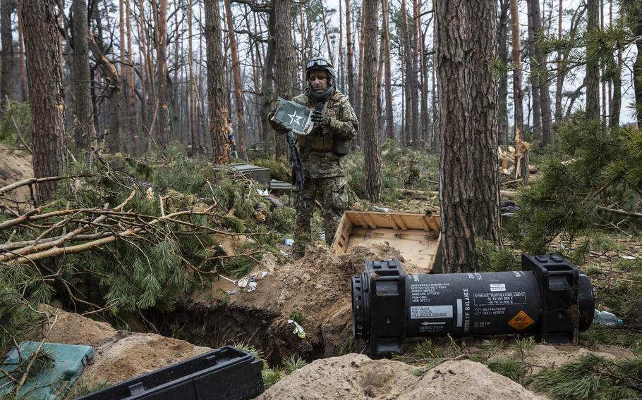 A Ukrainian soldier inspects Russian food rations, his U.S.-supplied Javelin antitank weapon at the ready, in Moshchun, Ukraine.