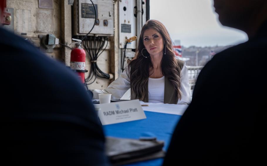 Noem sits across from Coast Guard crew members.