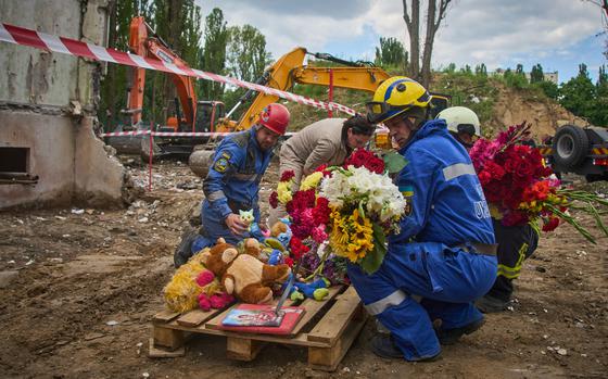 Rescuers lay toys and flowers on the site of Russia's Thursday night missile strike that hit a multistory residential house killing 31 civilians including five children in Kyiv, Ukraine, Friday, Aug. 1, 2025. (AP Photo/Efrem Lukatsky)