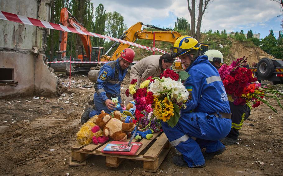 Rescuers lay toys and flowers on the site of Russia’s Thursday night missile strike.