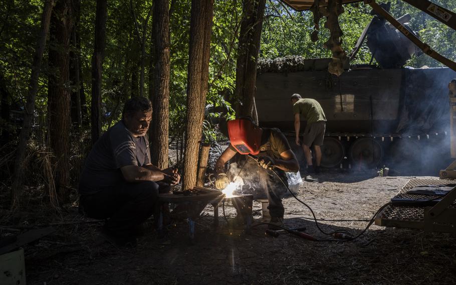 A welder works in front of a U.S.-supplied M113 armored personnel carrier at the workshop.