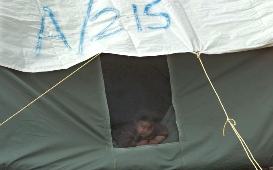 A young boy peers out the window of tent A/215 at the Brazda refugee camp. The number of refugees changes every day due to the steady stream of incoming refugees and the thousands of refugees that are temporarly going to different countries, but on the day this photo was taken — April 21, 1999 — it was believed to have reached approximately 22,000. 