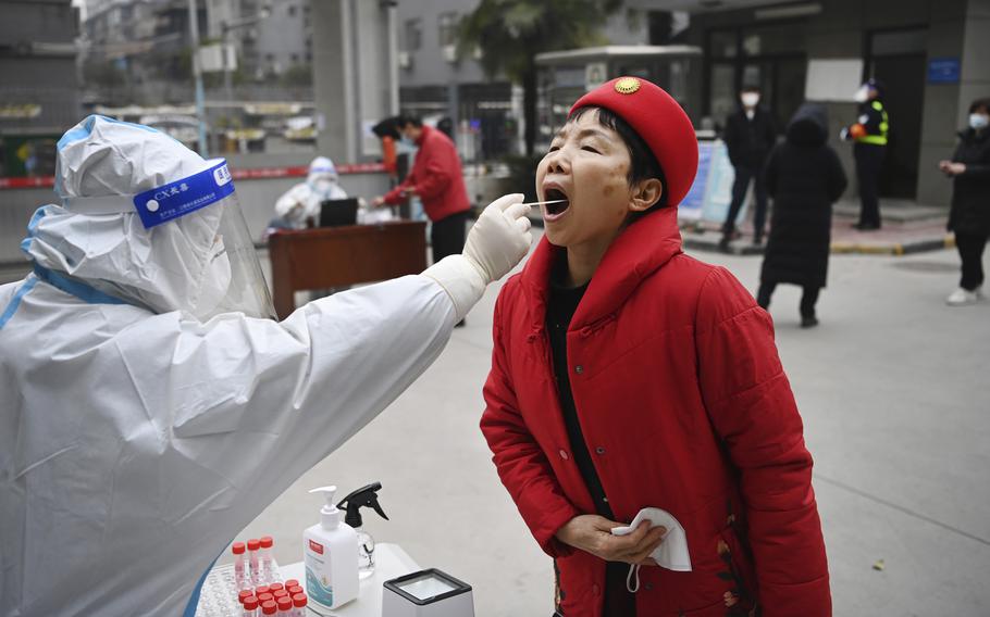 A worker wearing protective gear gives a COVID-19 test to a woman at a testing site in Xi’an in China’s Shaanxi Province, on Tuesday, Jan. 4, 2022. China is reporting a major drop in local COVID-19 infections in Xi’an, which has been under a tight lockdown for the past two weeks. 