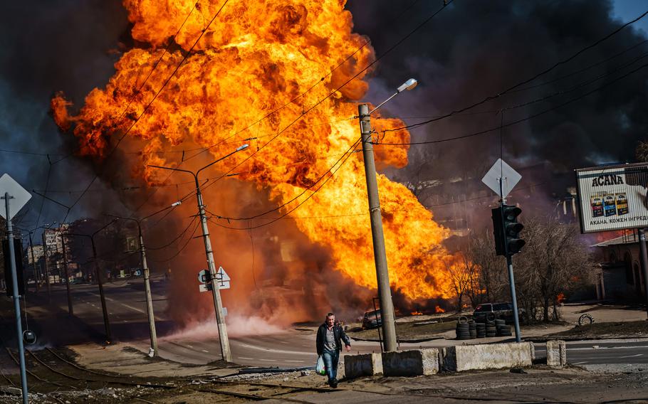 A man hurries away from a building that had just been struck by Russian bombardment in the Moskovskyi district in Kharkiv, Ukraine, on Friday, March 25, 2022.