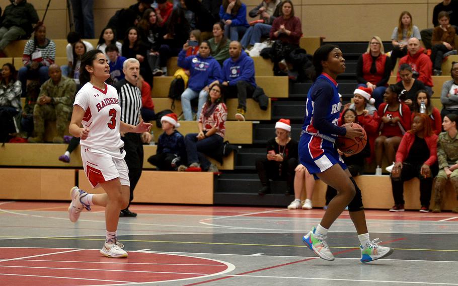 Ramstein’s Bralyn Jones, right, gets ready to go in for a layup during the Royals’ 50-19 win over Kaiserslautern, Dec. 13, 2022,  at Kaiserslautern High Schoo. At left is the Raiders’ Kimberly Guzman.