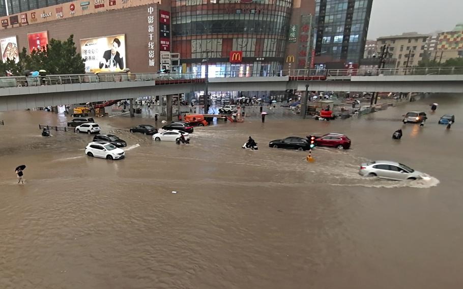 Vehicles are stranded after a heavy downpour in Zhengzhou city, central China's Henan province Tuesday. Heavy flooding has hit central China following unusually heavy rains, with the subway system in Zhengzhou inundated with rushing water.