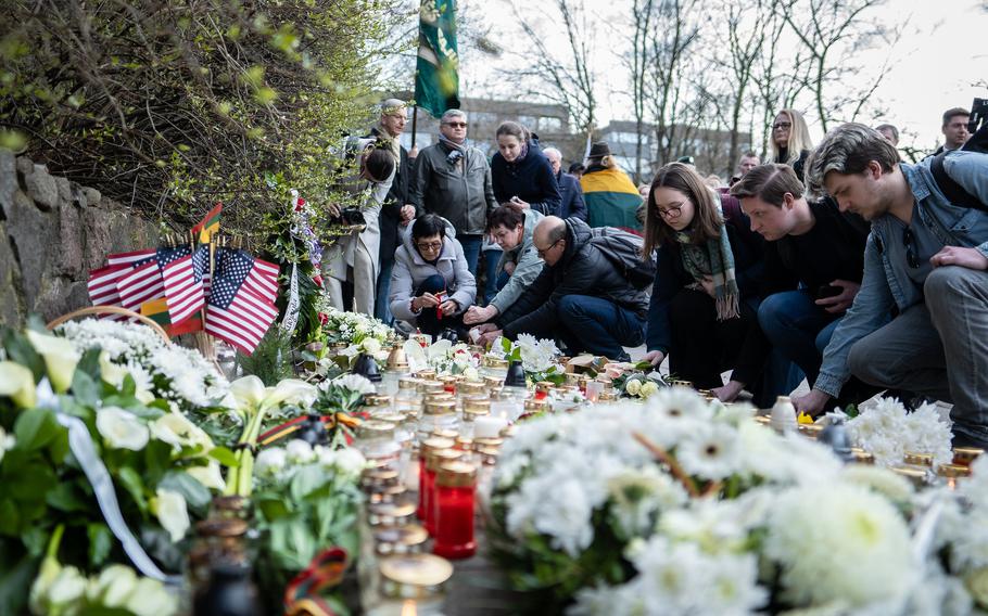 People lay flowers and light candles at a memorial for U.S. soldiers.