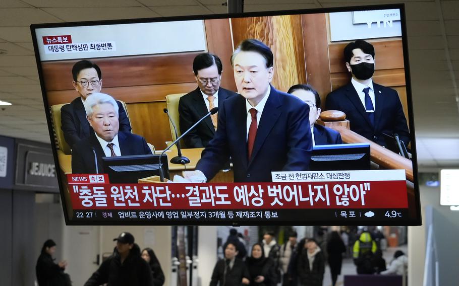 A TV screen shows a Korean man in a dark suit speaking in a courtroom.