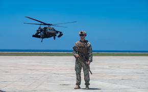 A U.S. Marine assigned to Joint Task Force Southern Guard stands guard on the flight line during an illegal alien removal flight at Naval Station Guantanamo Bay, Cuba, April 30, 2025. The JTF-SG is providing support to illegal alien holding operations led by the Department of Homeland security. (U.S. Air Force photo by 1st Lt. Nadia K. Rossin)