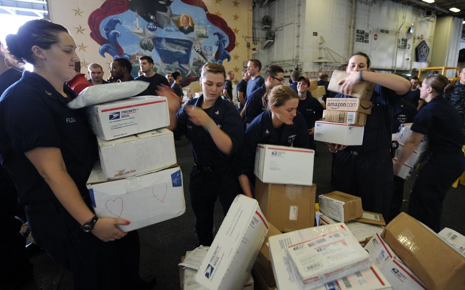 Sailors sort boxes during a mail call.