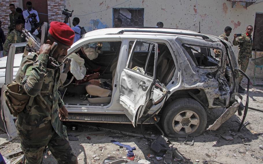 Security forces and others observe the remains of the vehicle in which Somalia’s government spokesperson Mohamed Ibrahim Moalimuu was wounded in a suicide bombing in Mogadishu, Somalia on Sunday, Jan. 16, 2022. 