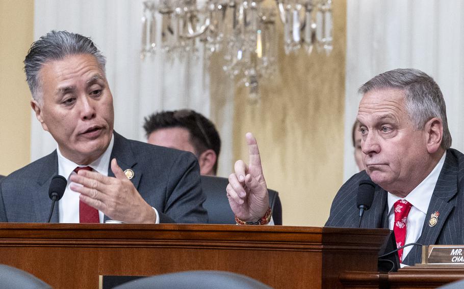 Two men in suits sitting next to each other arguing.