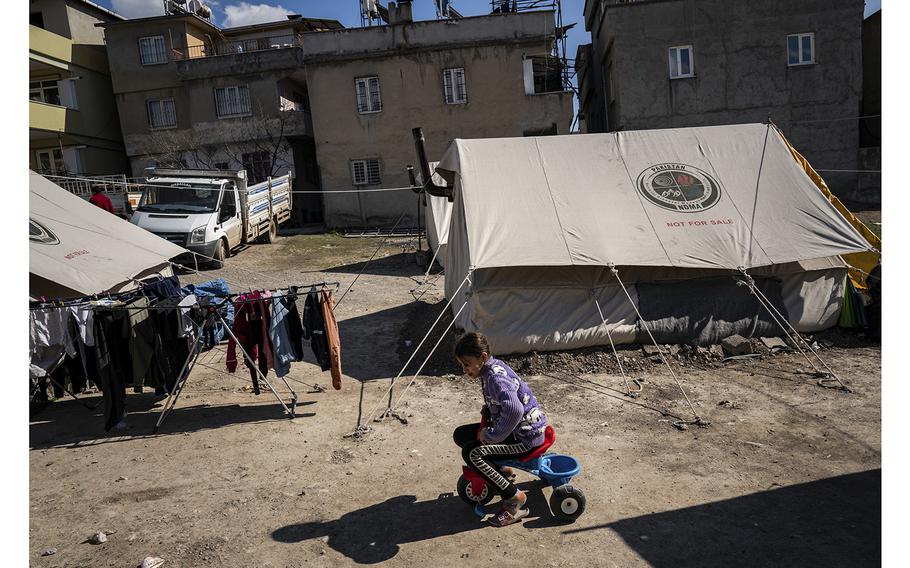 Abu Hussein’s daughter rides a tricycle amid the tents housing the extended family and their Turkish neighbors. 