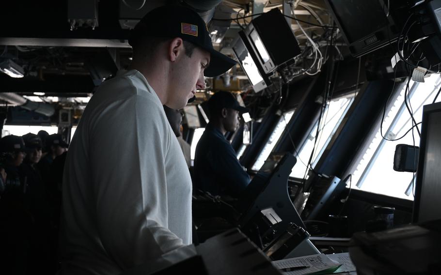 Sailors in a dark room, illuminated by the glow of computer screens.