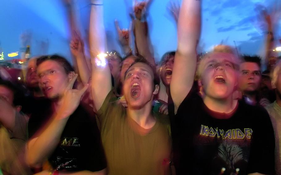 A blurry photo of concertgoers raising their hands and cheering.