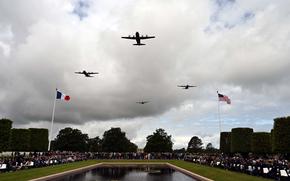 Military aircraft fly in formation over a cemetery.