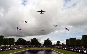 Military aircraft fly in formation over a cemetery.