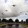 Military aircraft fly in formation over a cemetery.
