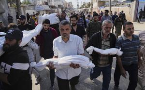 A group of Palestinian men walk down a street in Gaza carrying the white shroud-covered bodies of relatives killed in an airstrike.