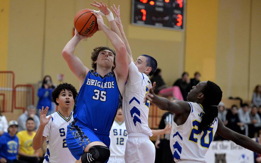 In a Division III game at the DODEA-Europe basketball finals in Baumholder, Germany, Brussels’ Mason Kleckner, drives to the basket against Sigonella’s Christopher Hedemand as teammates Jabriel Wells, left, and Deshawn Wallace watch. The Jaguars beat the Brigands 38-12.