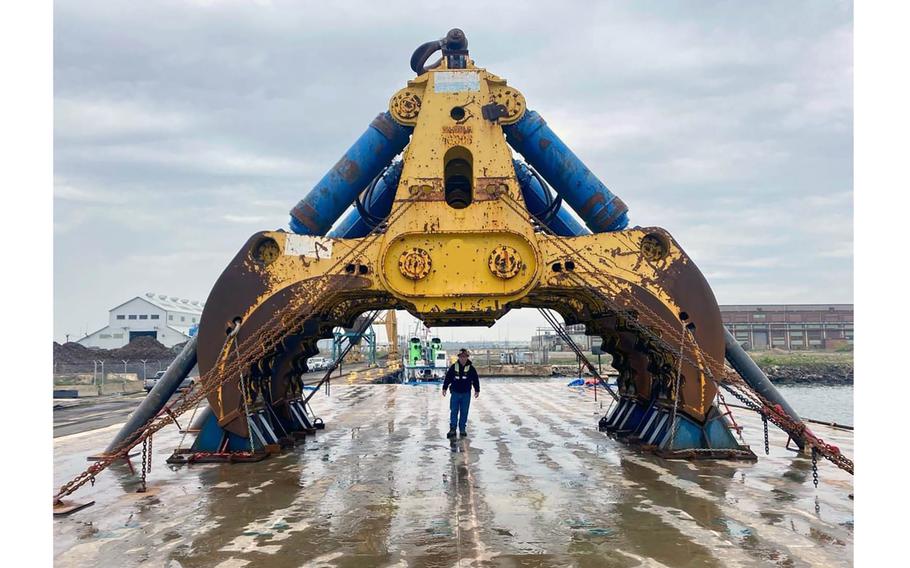A 200-ton salvage grab towers over a Key Bridge Response Unified Command longshoreman after the set of claws arrived in Sparrows Point over the weekend to clear wreckage from the bottom of the Patapsco River. The Dutch-made hydraulic grab has four independent claws that together can lift more than 1,000 tons. 