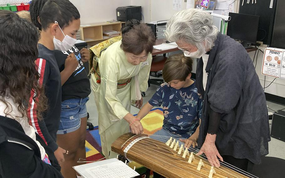 Japanese volunteers show fourth-graders how to play the koto, a traditional Japanese instrument, during the JaPANDAsia event at Joan K. Mendel Elementary School on Yokota Air Base, Japan, Thursday, May 4, 2023.
