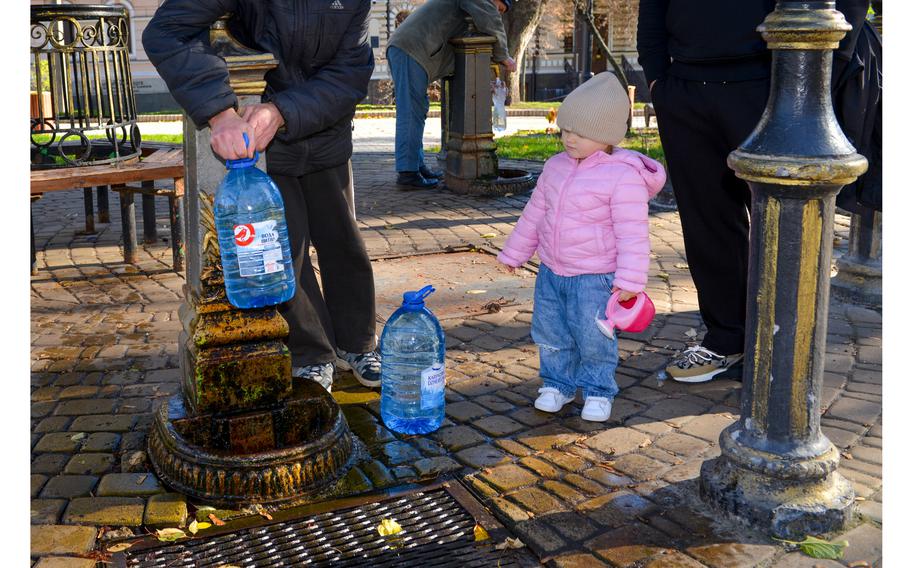 Liza, who is from Kyiv, Ukraine, waits to refill her toy watering can at a public fountain in Taras Shevchenko Park on Oct. 31, 2022. At least 50 residents came to the park to get water, with some saying they were regulars at the pump and some saying they came due to a Russian missile attack that morning left many homes and offices without water.