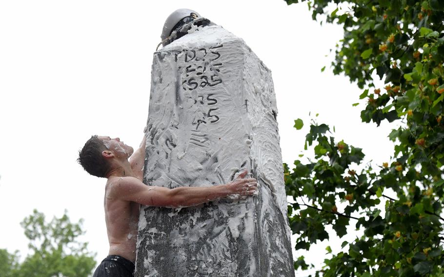 USNA Midshipman 4th Class Ben Leisegang, 20, of 4th Company, from Rancho Santa Margarita, Calif., places the upperclassman cover on top of the Herndon Monument after removing the plebe Dixie Cup hat, in a time of 2:19:11. (Paul W. Gillespie/Staff)