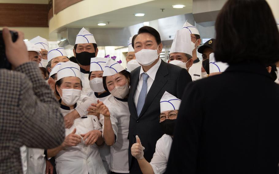 Then-president elect Yoon Suk Yeol poses with deli workers at Camp Humphreys, South Korea, April 7, 2022.