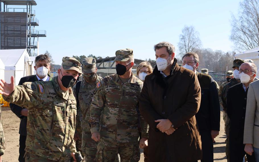 Brig. Gen. Joseph Hilbert, left, commander of the 7th Army Training Command, shows Army Chief of Staff Gen. James McConville, center, and Bavarian governor Markus Soeder, right, where soldiers are waiting for their Bavarian breakfast at Grafenwoehr Training Area, Germany, March 11, 2022. 