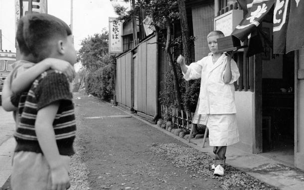 Two Japanese boys watch as Bill leaves the Soba shop in Shinjuku for another delivery. 