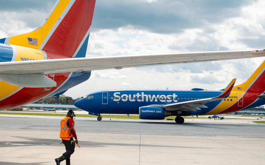 A ramp agent walks past Southwest Airlines airplanes parked on the runway.