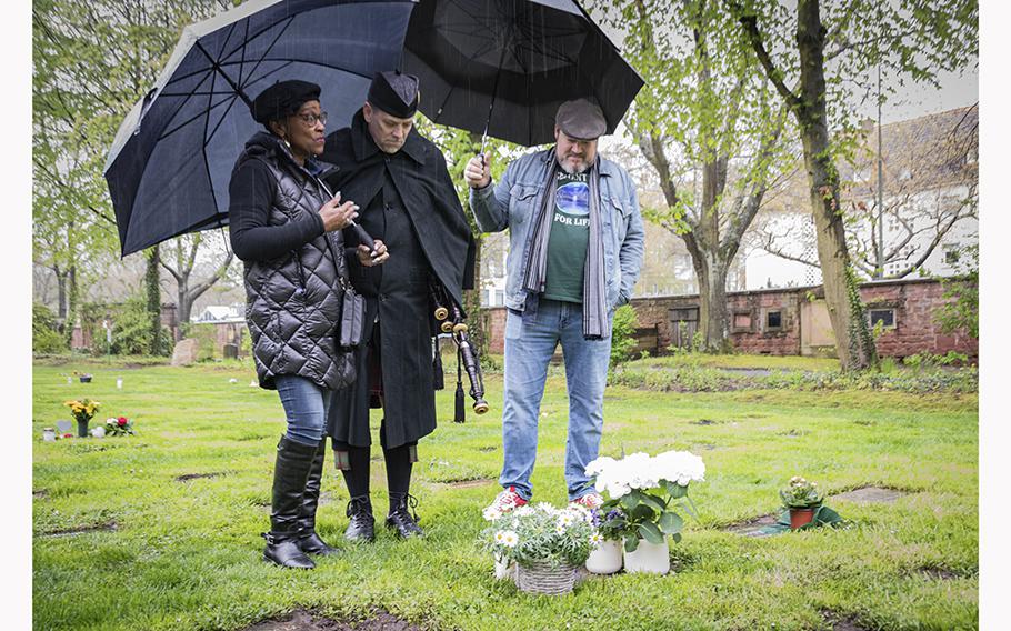 Flossie Adams, left, Shane Schiermeier and Mike Gosling visit the gravesite of Ronny Coleman on Friday, April 28, 2023. Coleman, who worked at an AAFES Express shop on Kleber Kaserne, across the street from the cemetery, had been in an unmarked grave for a year until workers on Kleber bought a gravestone for him. 