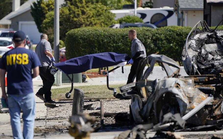 Officials from the San Diego County medical examiners office remove a gurney carrying remains from the site of a plane crash Tuesday, Oct. 12, 2021, in Santee, Calif. Recordings indicate the pilot of a twin-engine plane nose-dived into this San Diego suburb Monday despite a growingly concerned air traffic controller who repeatedly warned the pilot to climb in altitude — information that will be examined by investigators who arrived at the crash scene on Tuesday. 