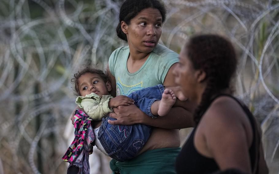 A woman carries her child after she and other migrants crossed the Rio Grande and entered the U.S. from Mexico, to be processed by U.S. Customs and Border Protection, Saturday, Sept. 23, 2023, in Eagle Pass, Texas. The image was part of a series by Associated Press photographers Ivan Valencia, Eduardo Verdugo, Felix Marquez, Marco Ugarte Fernando Llano, Eric Gay, Gregory Bull and Christian Chavez that won the 2024 Pulitzer Prize for feature photography.