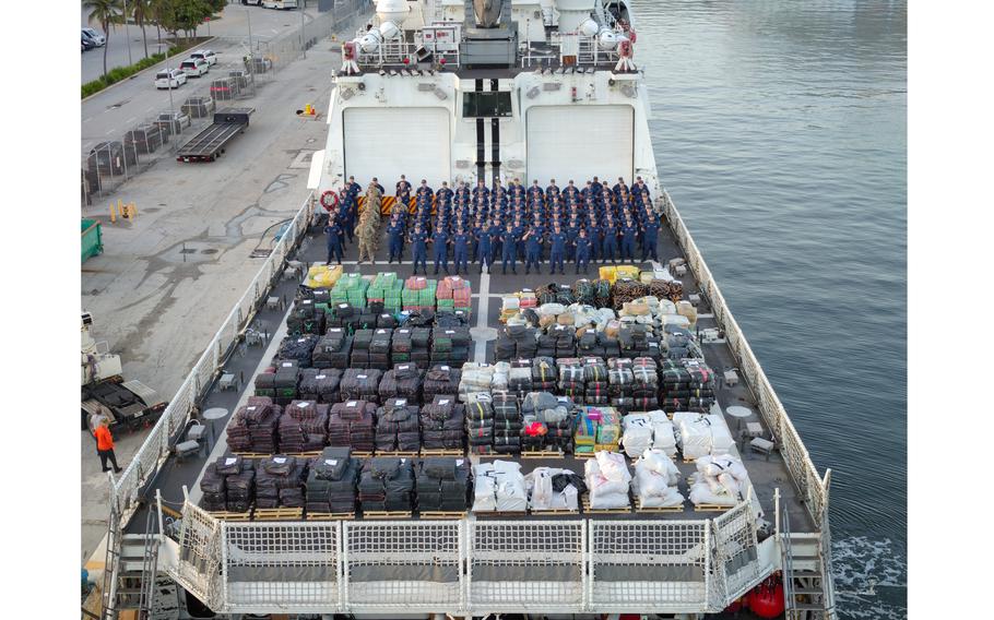 Containers of drugs fill the ship’s deck, with the crew standing in the background.