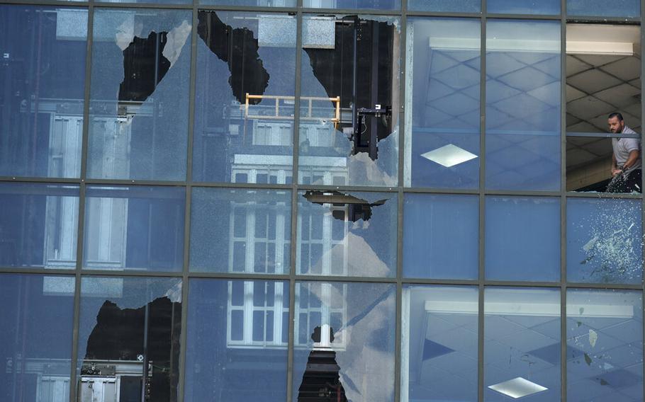 A man clears broken glass from a damaged window a day after violent clashes between Palestinians militants and Palestinian security forces in the West Bank city of Nablus, Sept. 21, 2022.