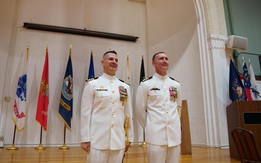Capt. Les Sobol, left, the new commander of Yokosuka Naval Base, Japan, stands with outgoing leader Capt. Rich Jarrett during a ceremony at the base theater, Friday, July 8, 2022. 