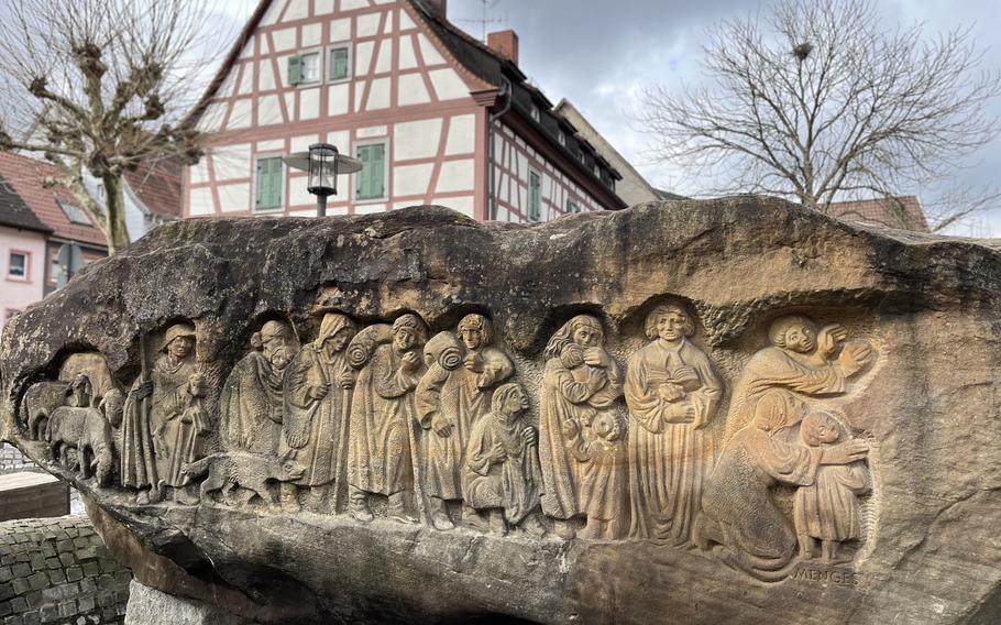 A Baroque-period granite sculpture stands on square in front of a church in Otterberg.