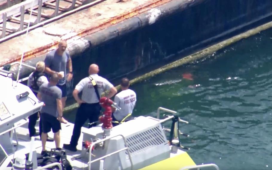A screengrab from a video shows fire rescue officials speaking to other people on a boat in the water.