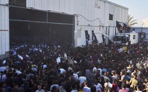 Hundreds of people rushing into a warehouse, with some ripping through the walls.